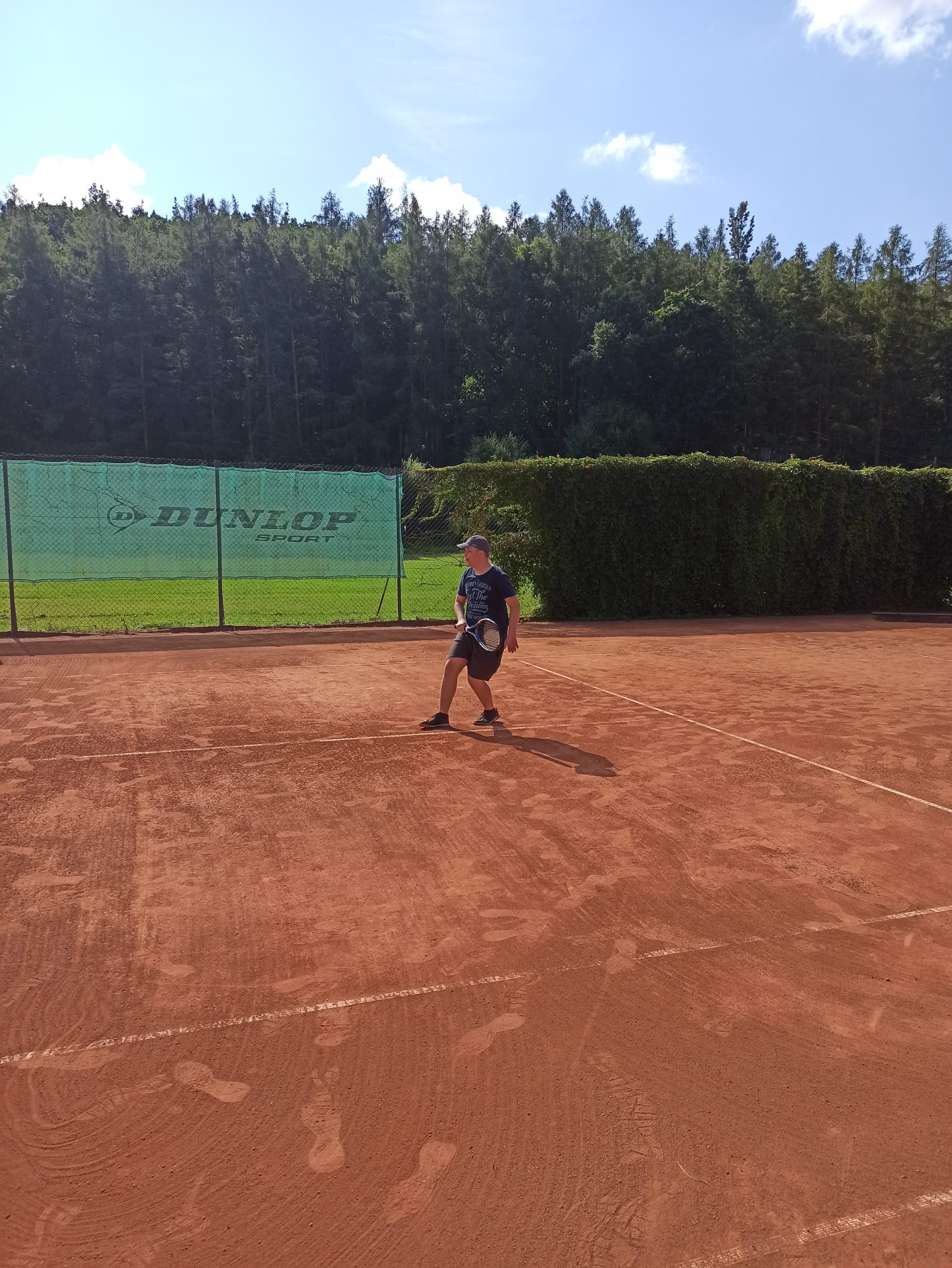 Wychowanek gra w tenisa ziemnego na korcie 