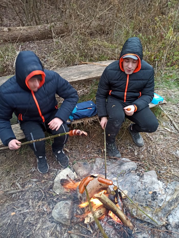 Wychowankowie przy ognisku smażą kiełbaski
